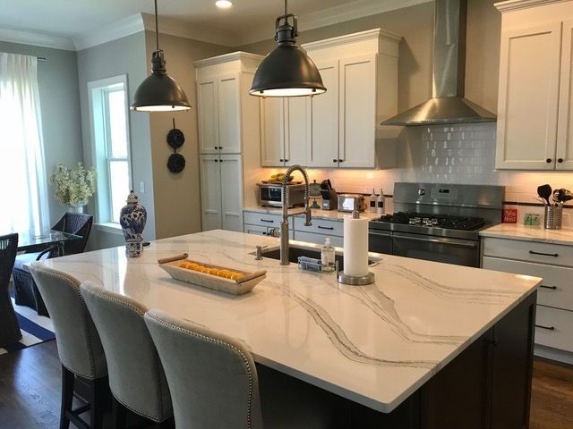 A kitchen with white cabinets and a large island in the middle.