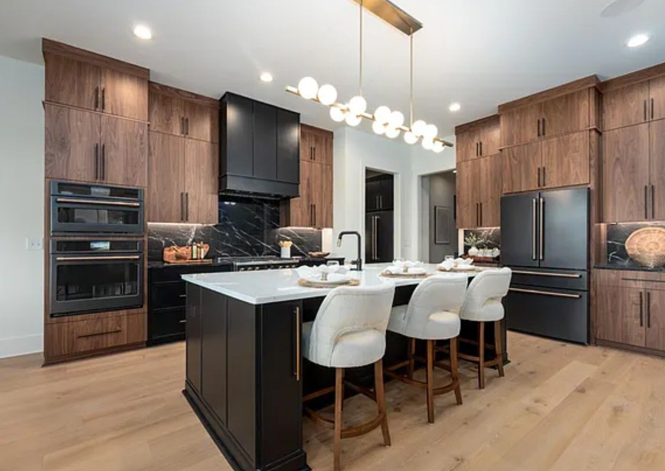 Modern kitchen with black island, wood cabinets, black appliances, and white countertops.