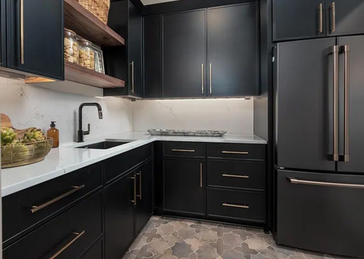 Dark blue kitchen with white countertops, black sink, and stainless steel refrigerator.