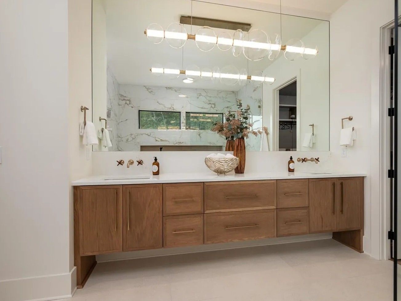 Modern bathroom with wood vanity, large mirror, and overhead lighting.