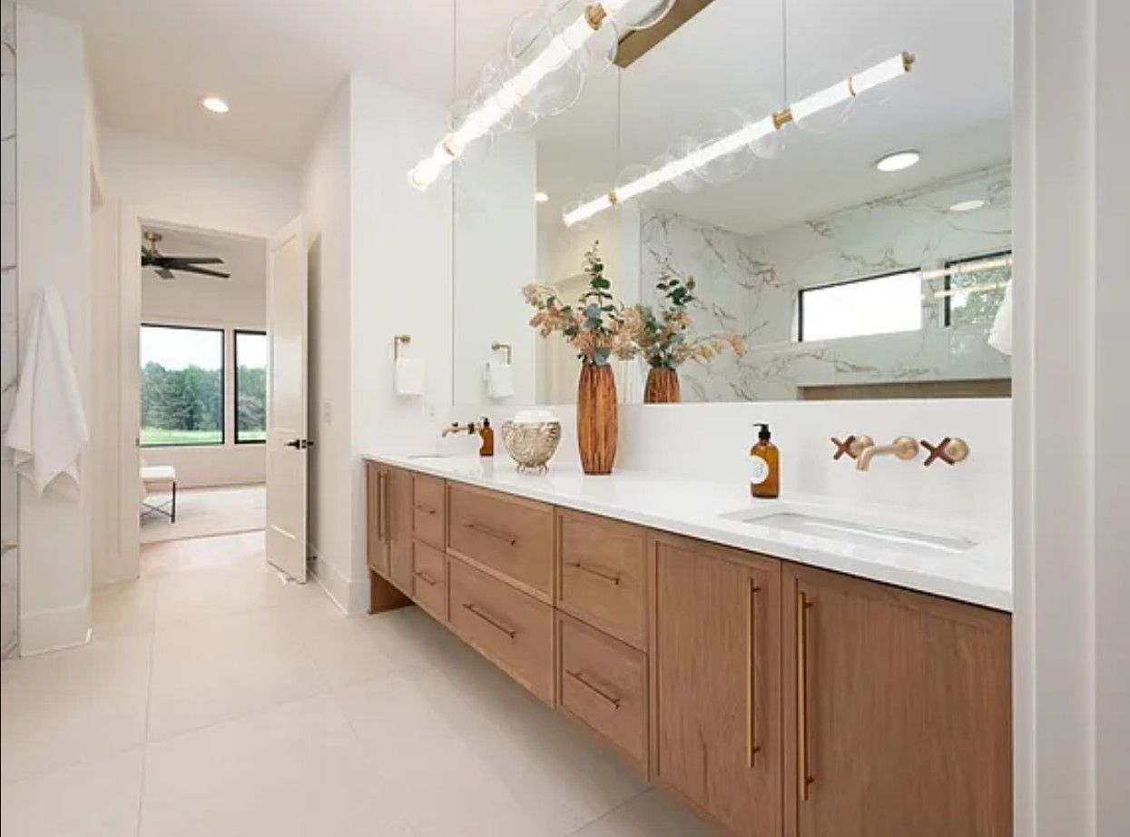 Modern bathroom with wood vanity, large mirror, and neutral tones.