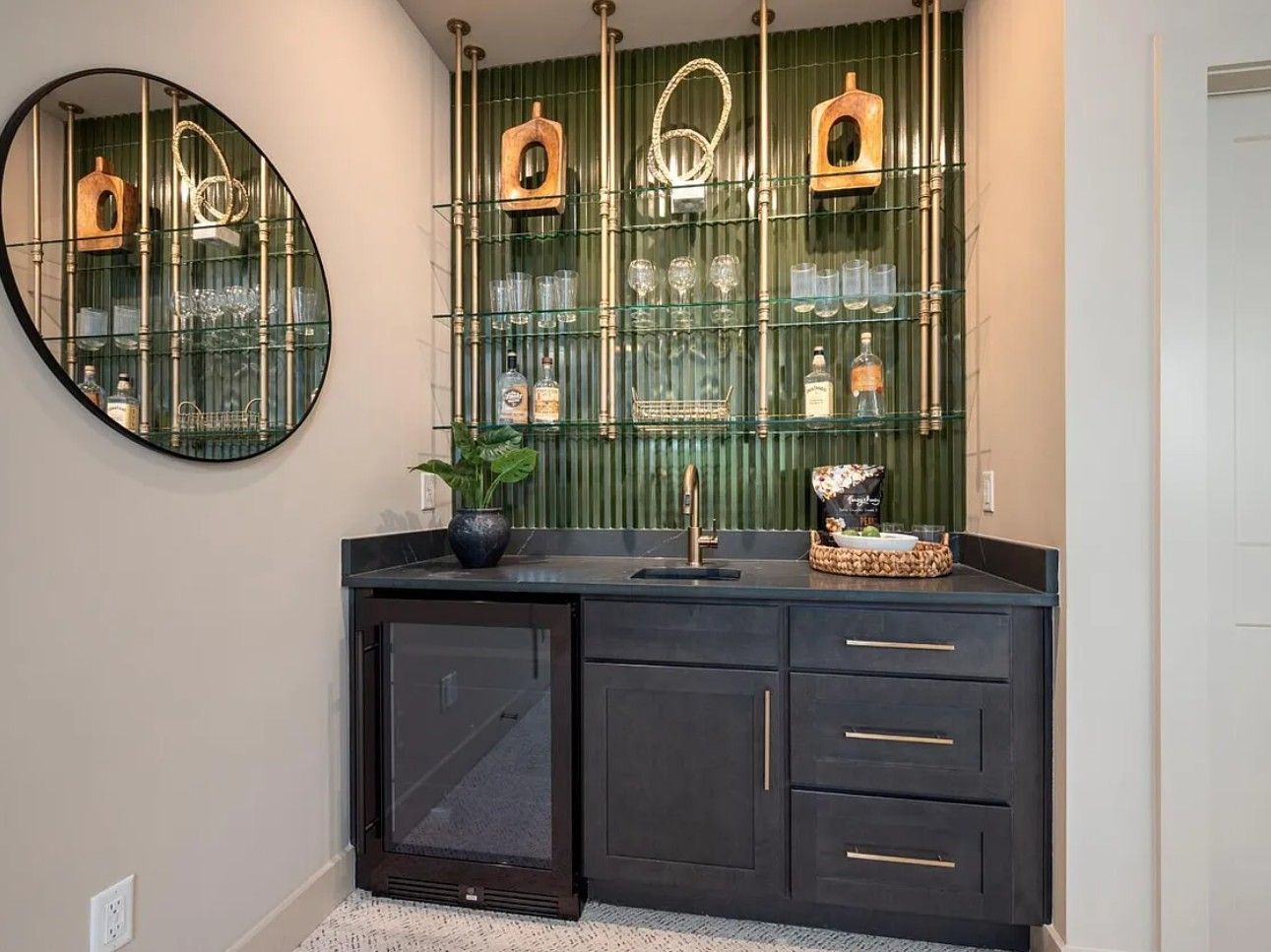 Dark green home bar with gold accents, mirror, and cabinet.