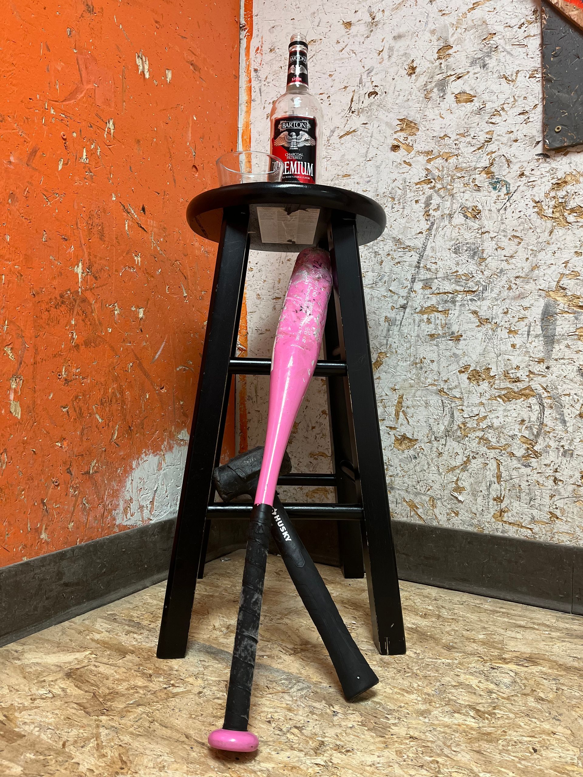 A pink baseball bat is sitting on top of a black stool.