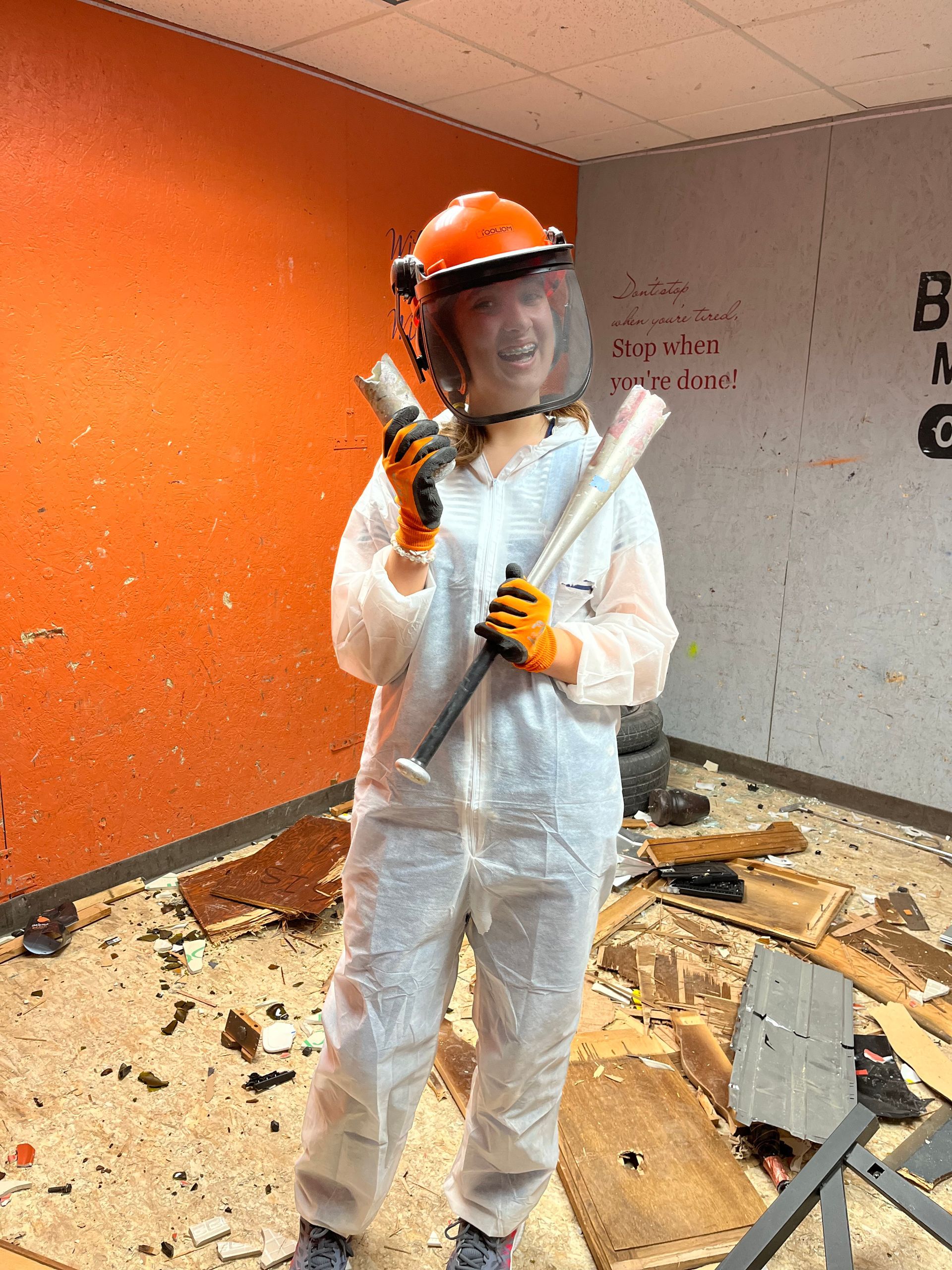 A woman in a white suit is holding a bat and a hammer.