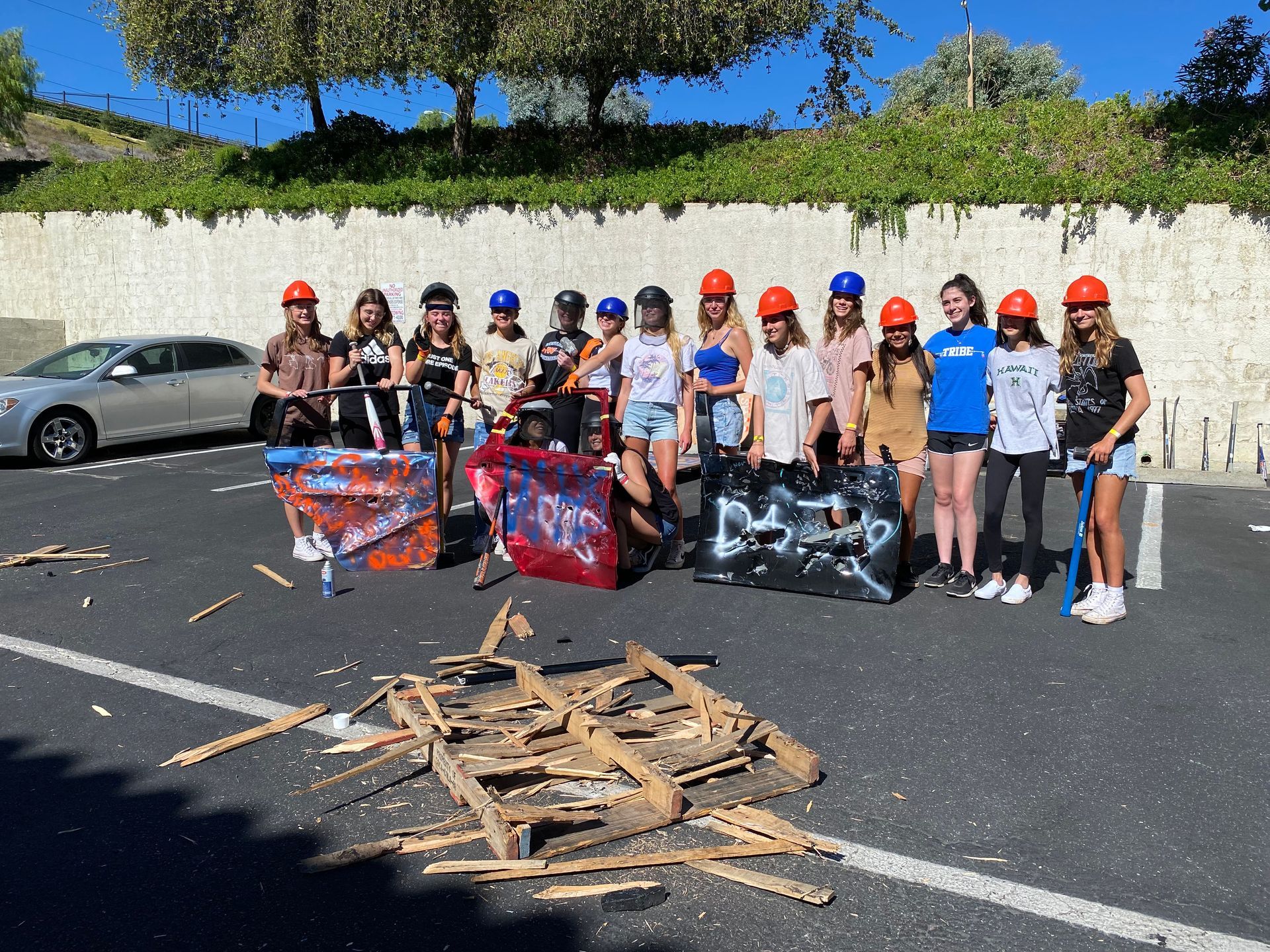 A group of people wearing hard hats are standing in a parking lot.