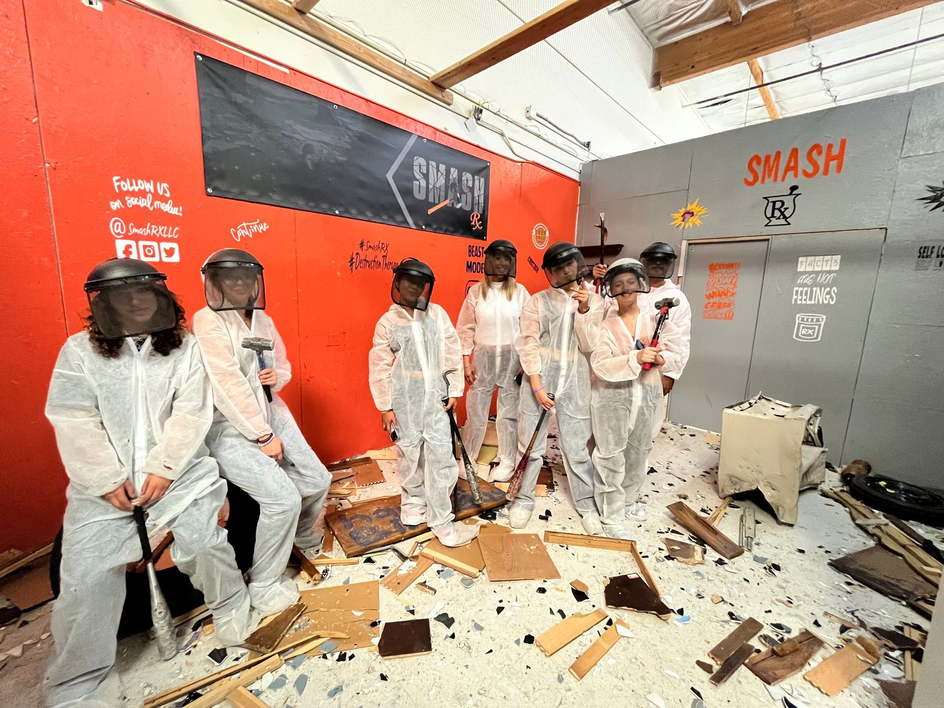 A group of people are standing in a room with a smash sign on the wall.