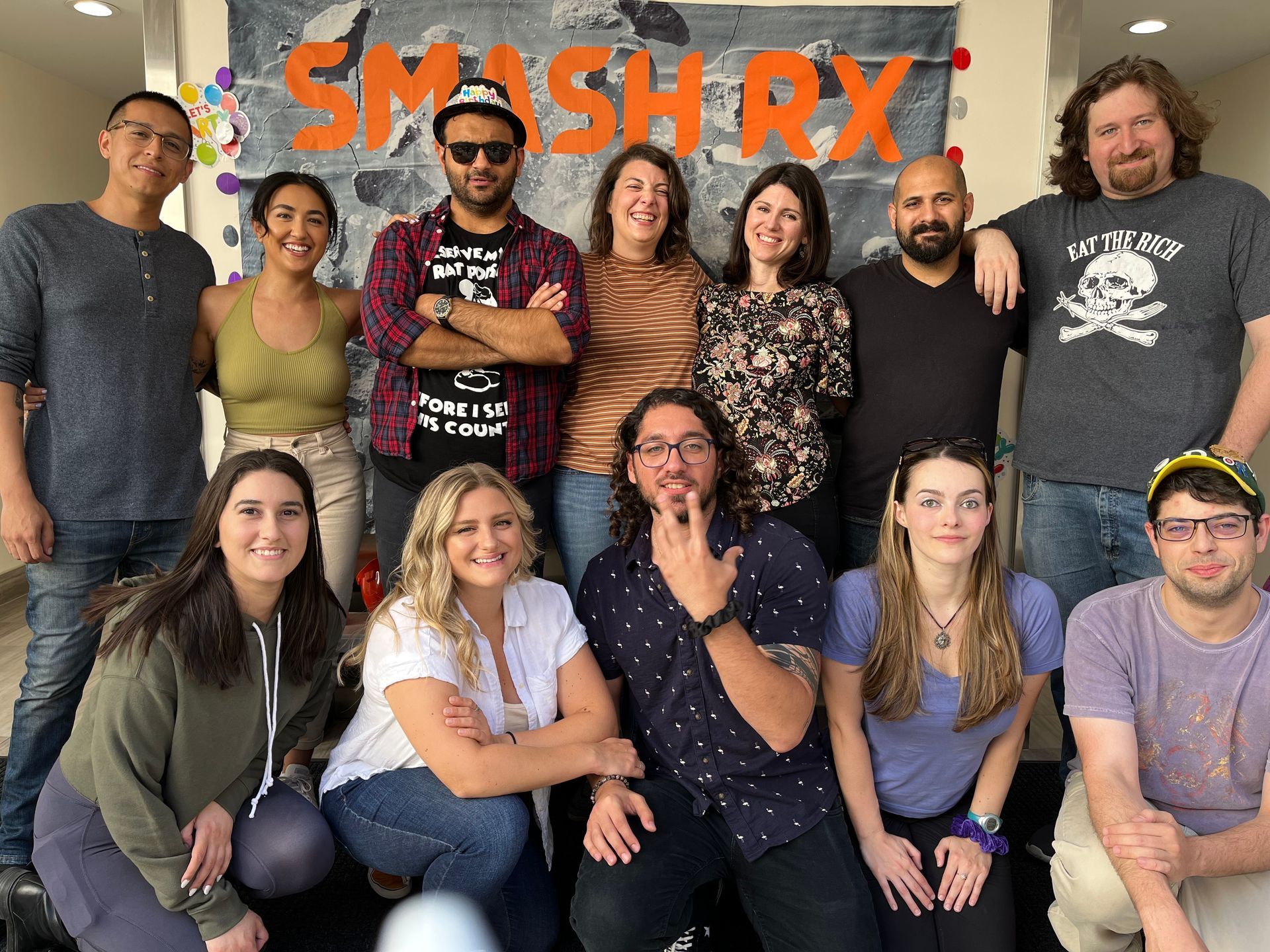A group of people are posing for a picture in front of a banner that says smash rx.