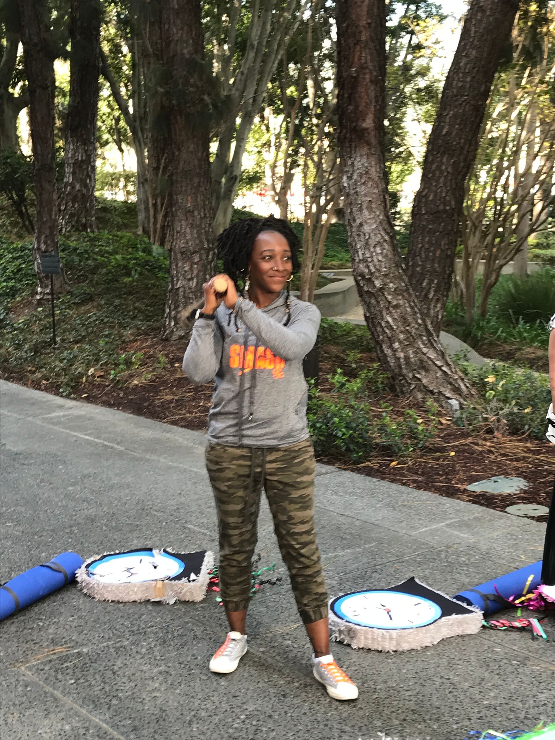 A woman is standing on a sidewalk holding a tennis racket.