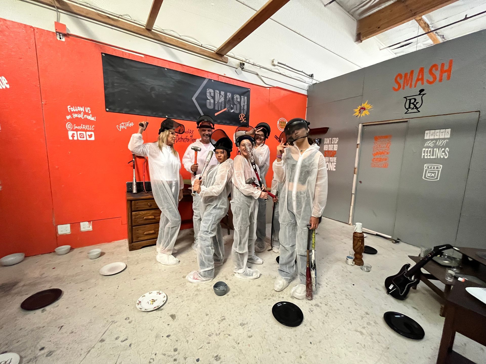 A group of people are standing in a room with plates on the floor.