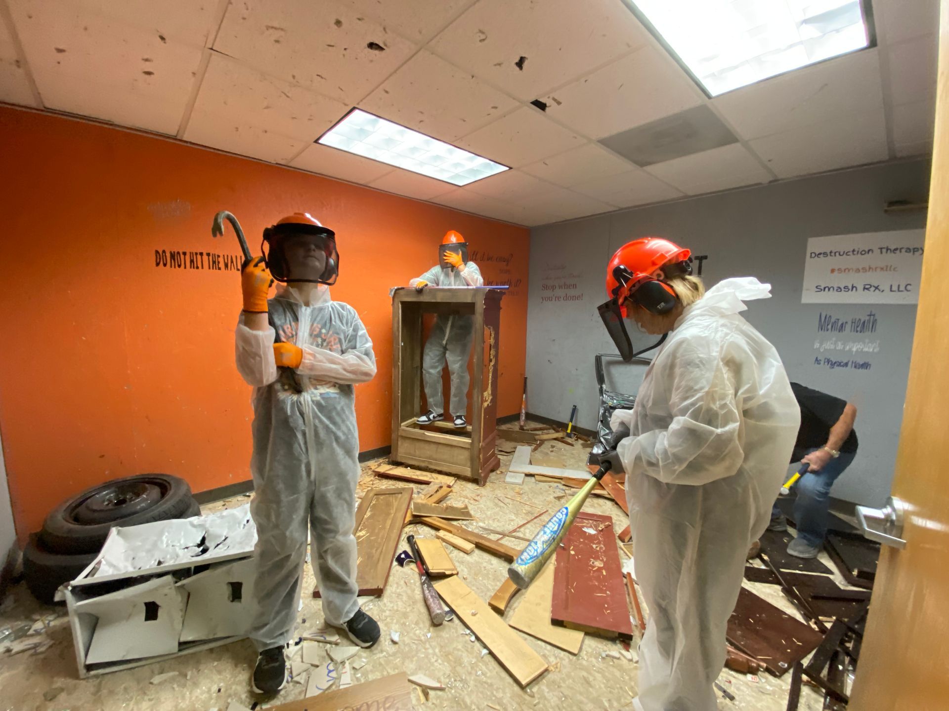 A group of people in white suits are standing in a room with a hammer.