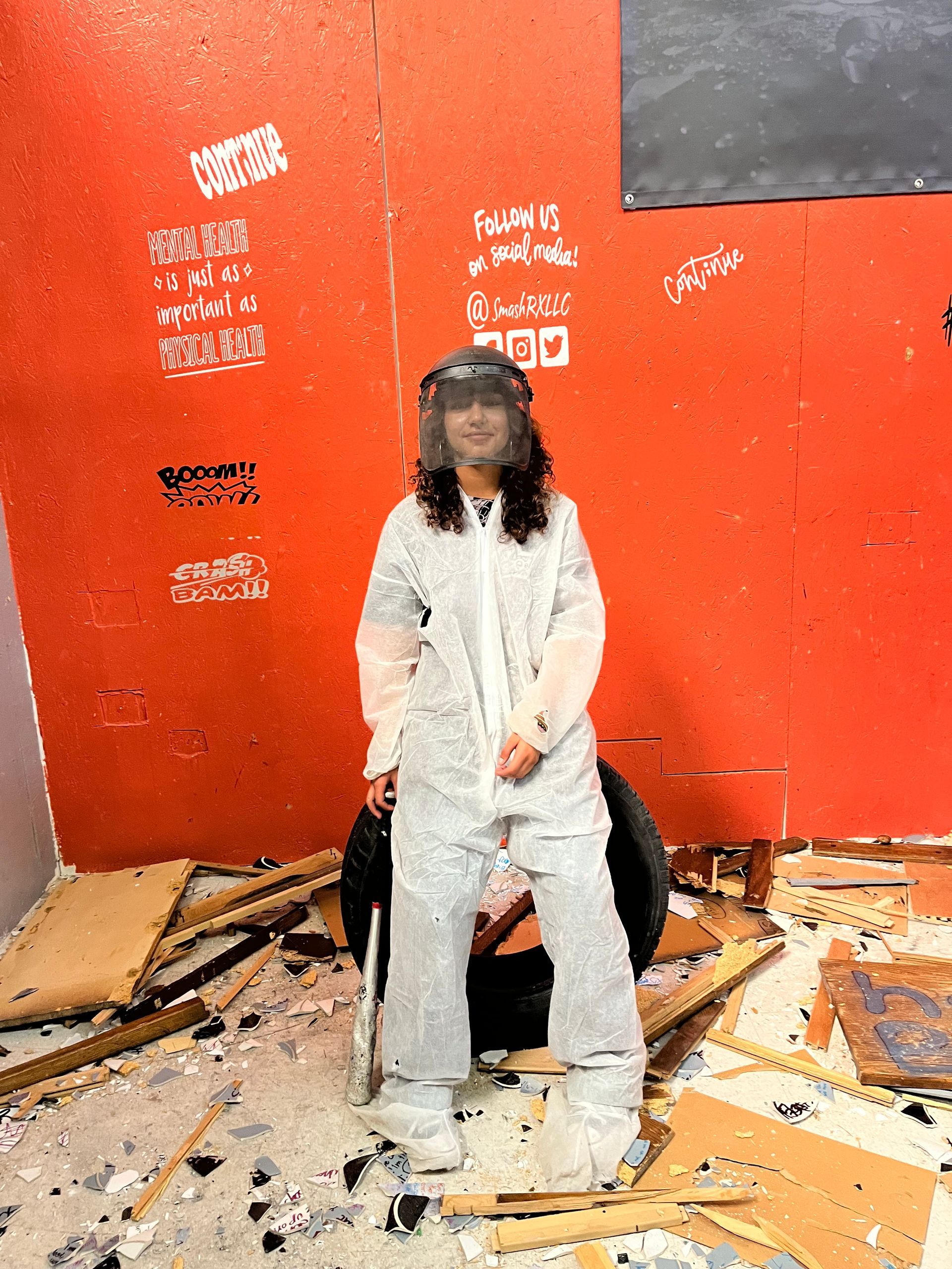 A woman in a white suit is standing in front of a red wall.