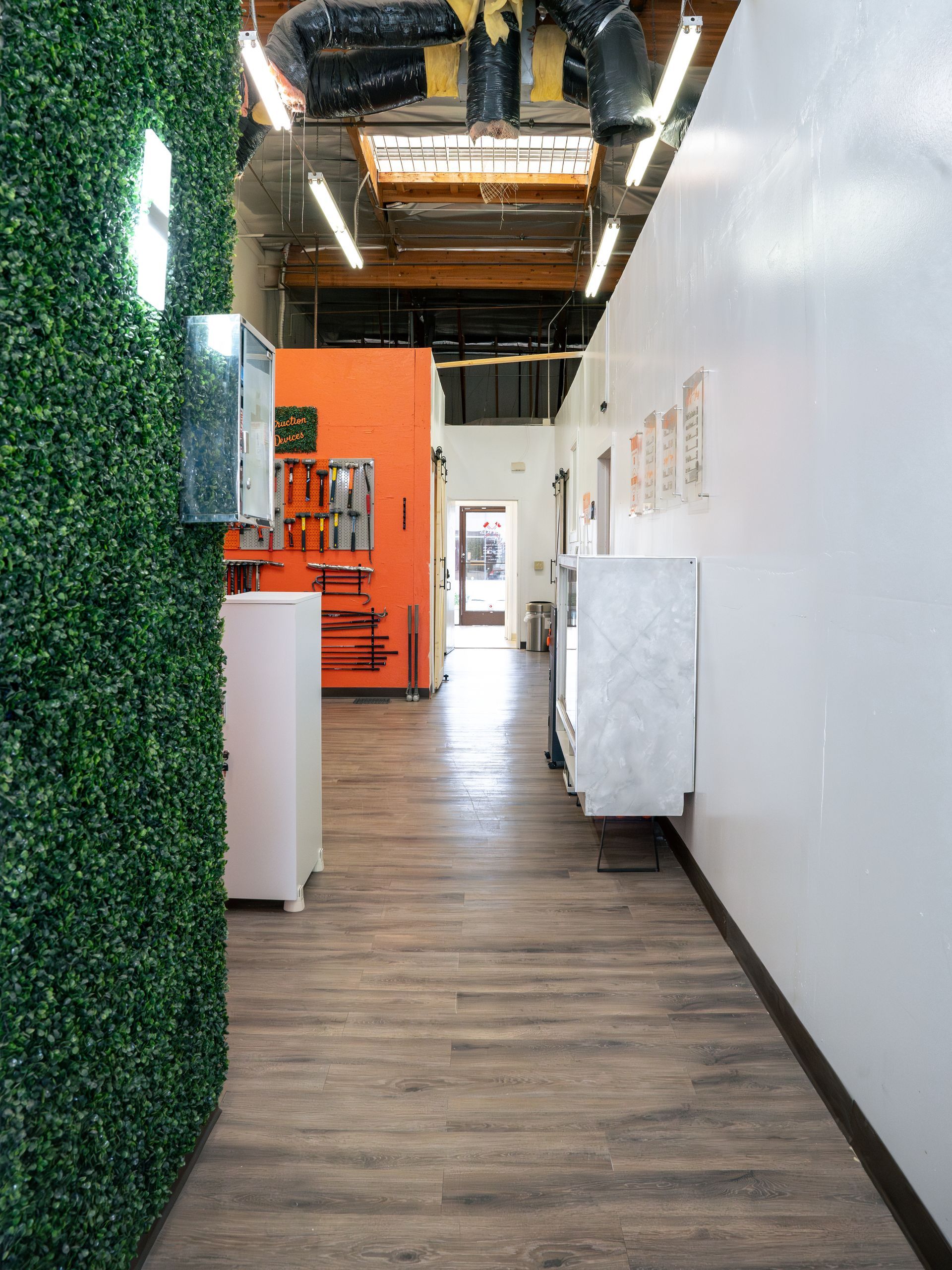 A long hallway in a building with wooden floors and a green wall.