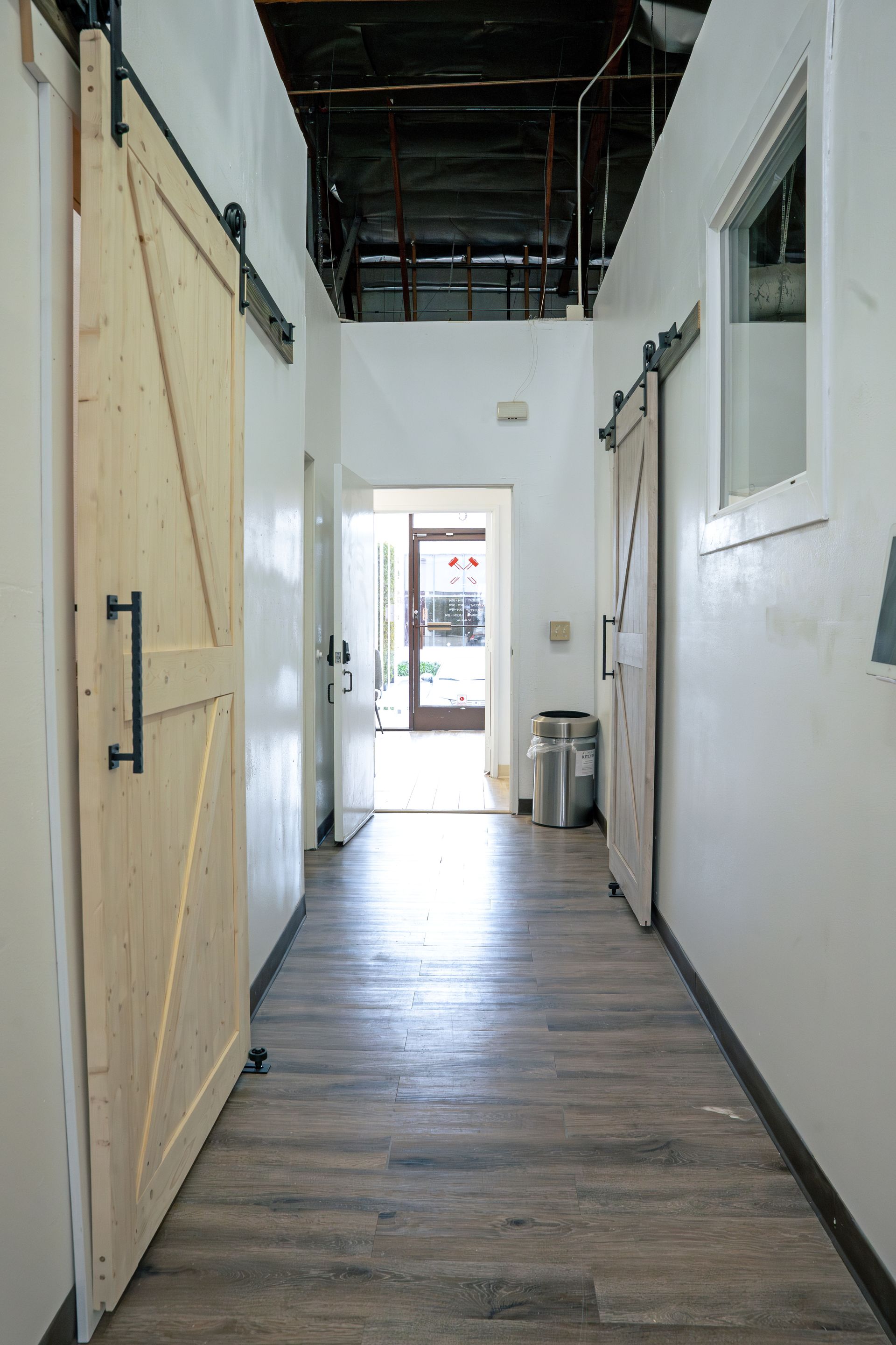 A hallway with sliding barn doors and a trash can.