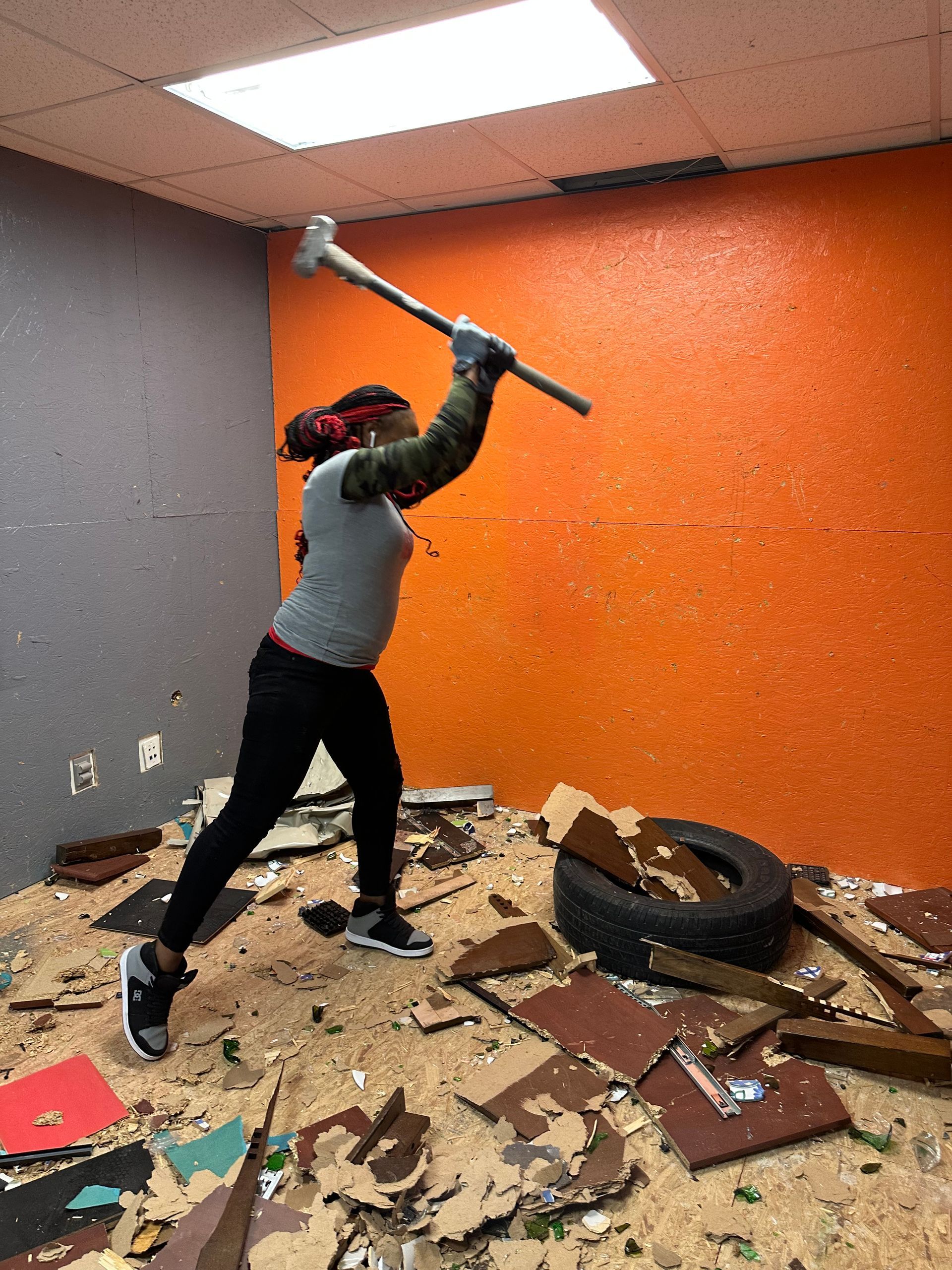 A woman is holding a large hammer in a room.