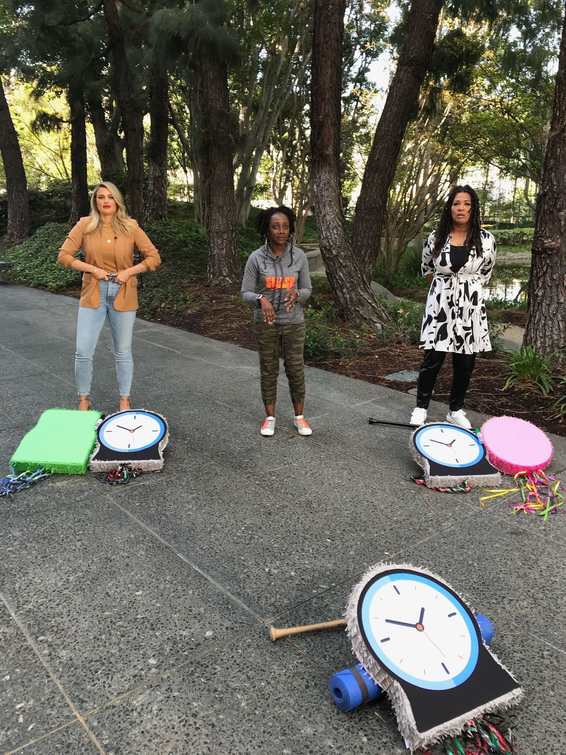 A group of people standing next to clocks on the ground.