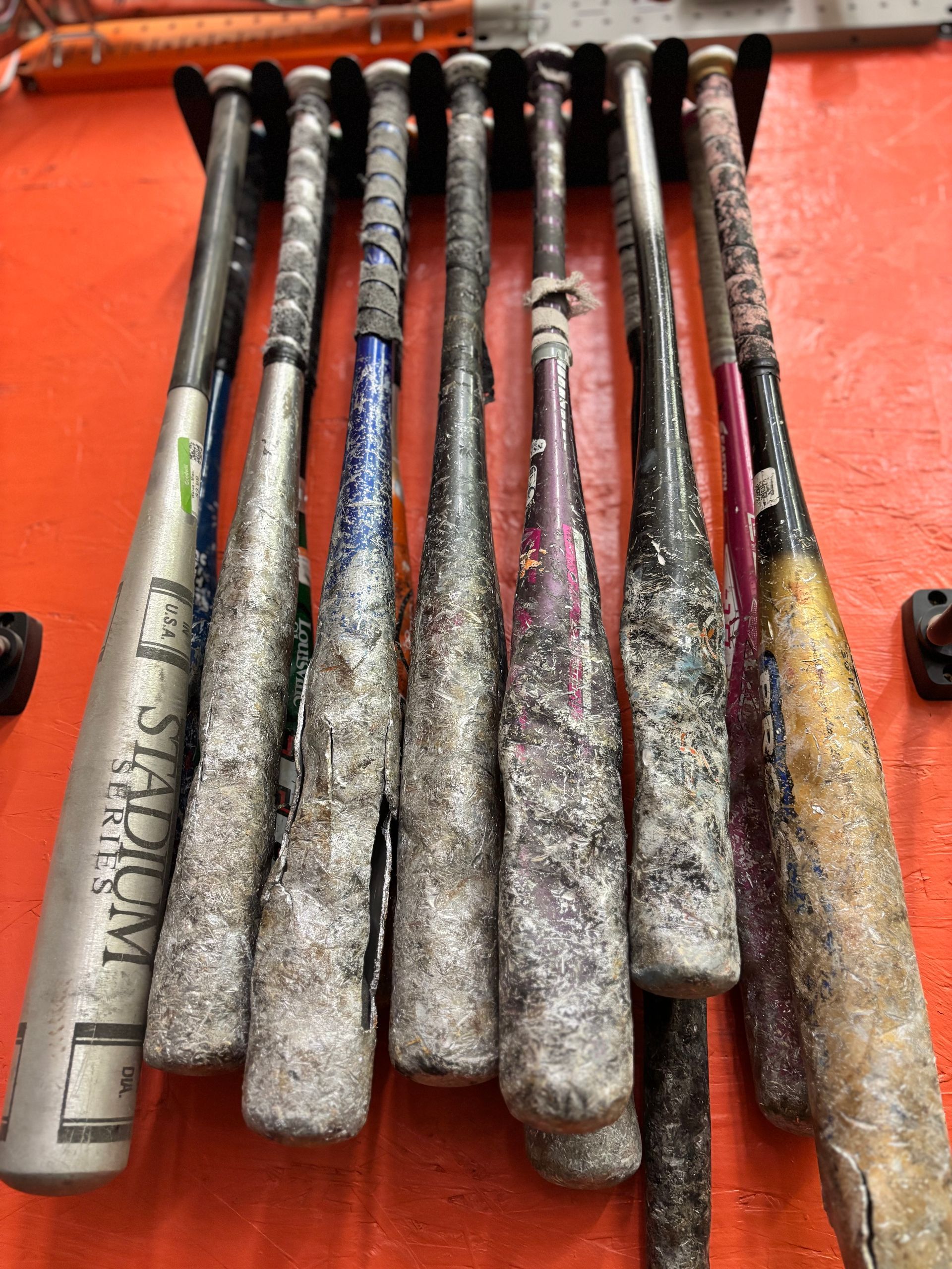 Worn out baseball bats in a wall rack