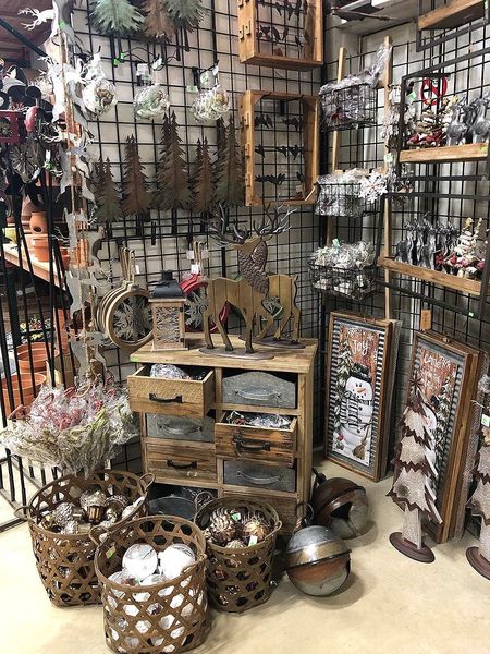 A rustic display of home decor, featuring baskets, drawers, frames, and metal sculptures in a store setting.