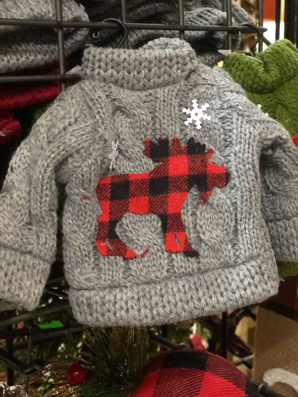 Gray knitted Christmas ornament of a sweater, featuring a buffalo plaid moose and a snowflake.