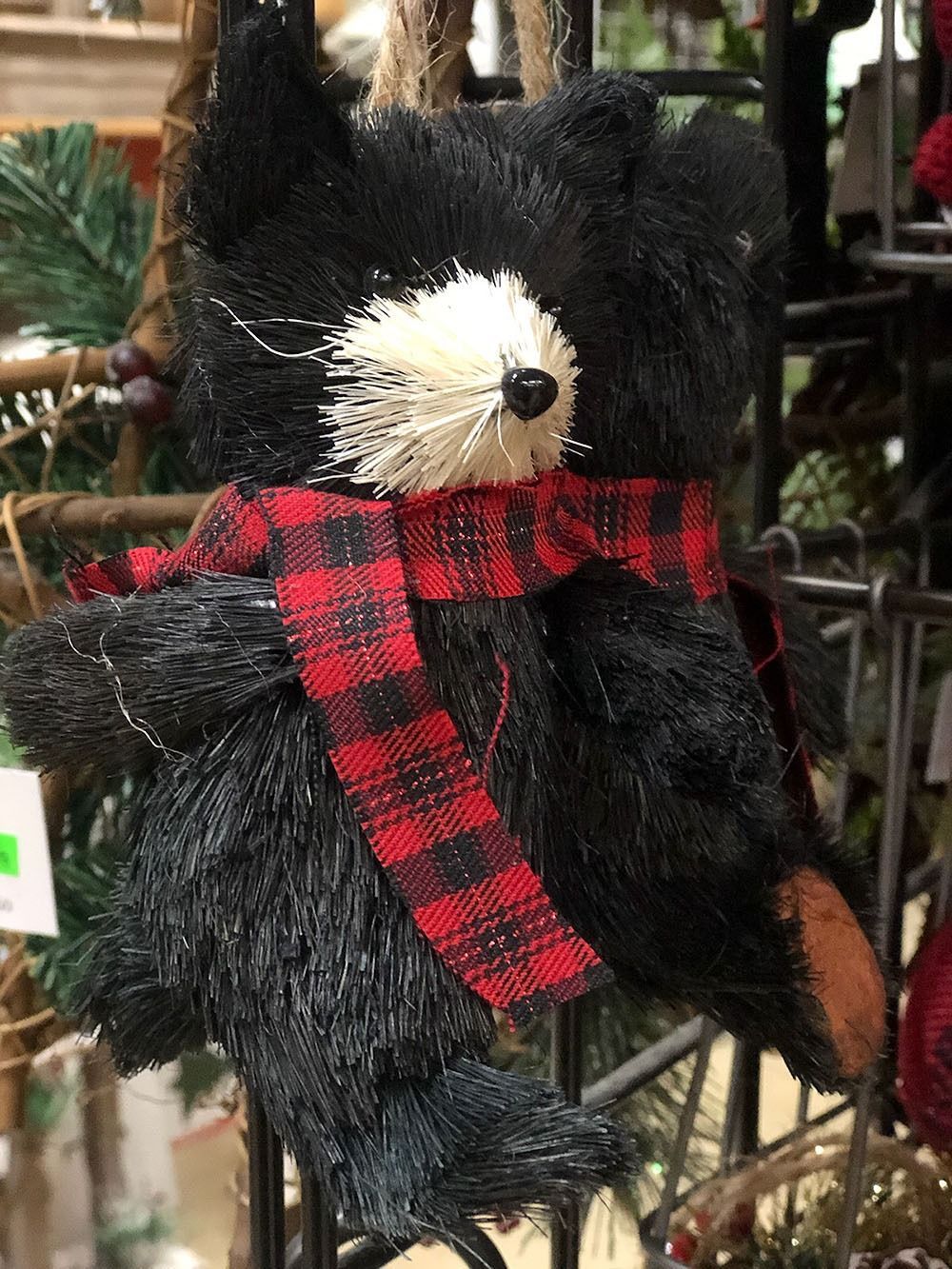 Black bear ornament with red plaid scarf, white snout, and brown feet.