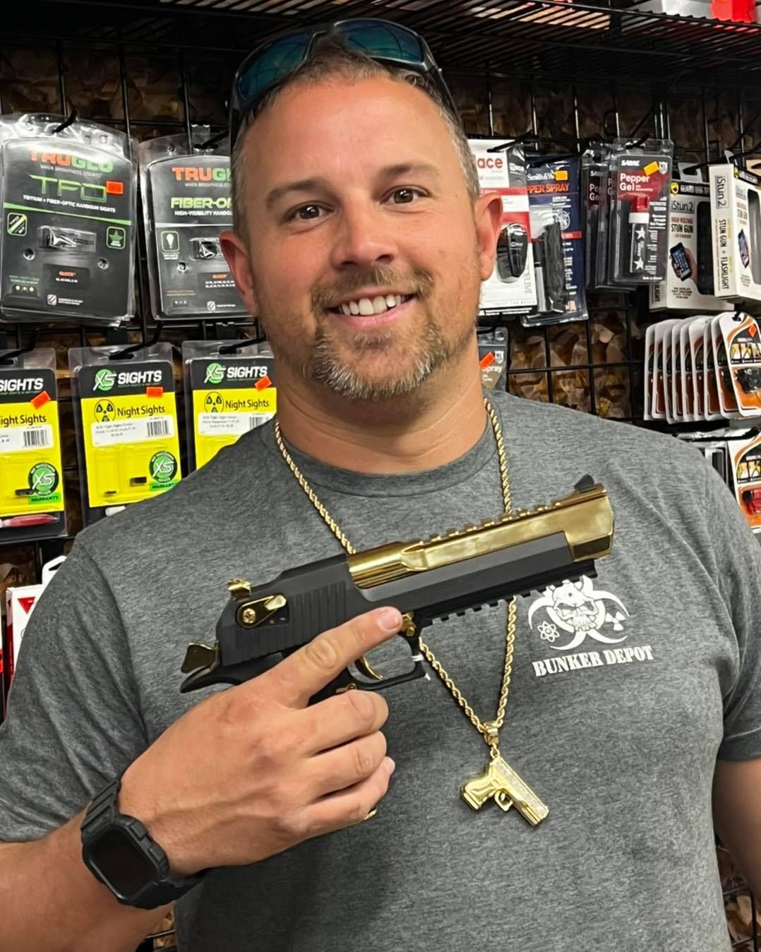 A guy wearing a grey shirt is holding a gun inside the gun store.