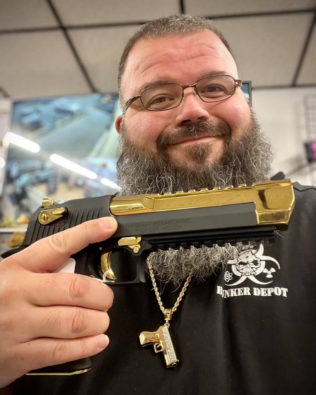 A guy with a long beard is holding a gun.
