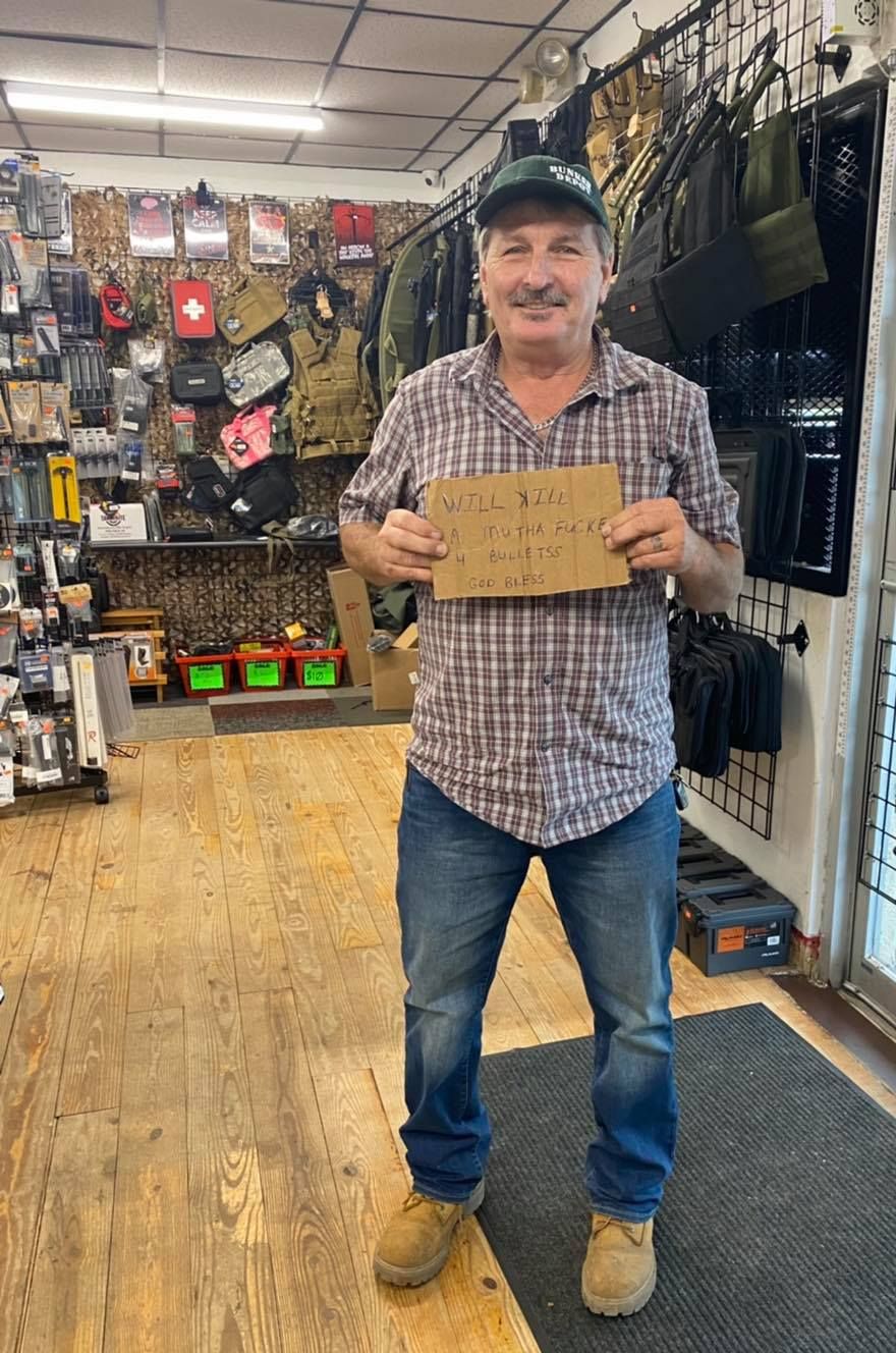 A man is standing in a store holding a sign.