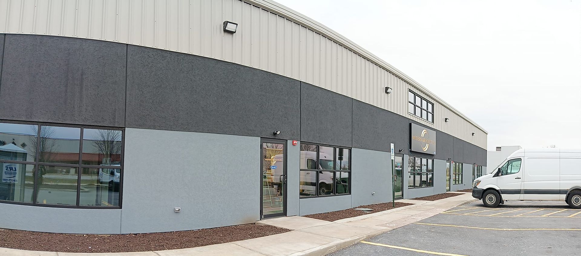 Exterior view of a commercial building with a white van parked outside.