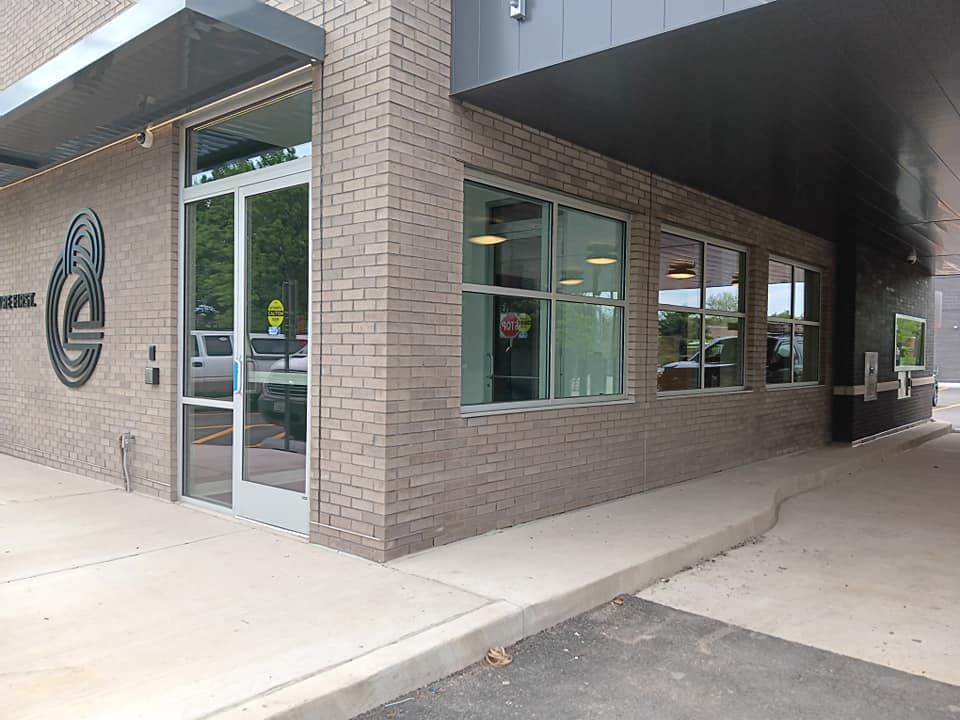 Modern brick building corner with windows and a drive-through lane. Gray brick and dark trim.