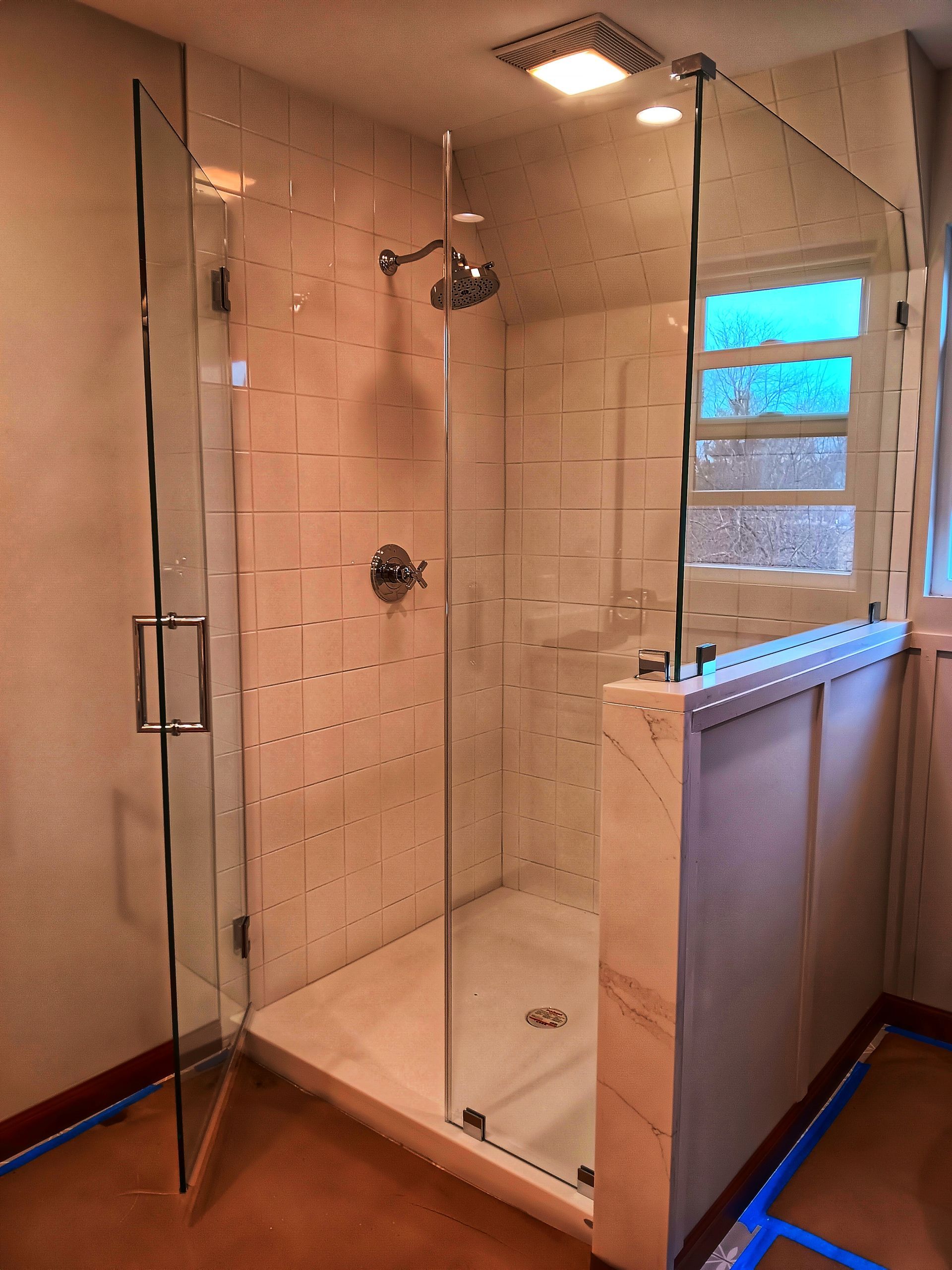 Glass shower enclosure with white tile walls and chrome fixtures.