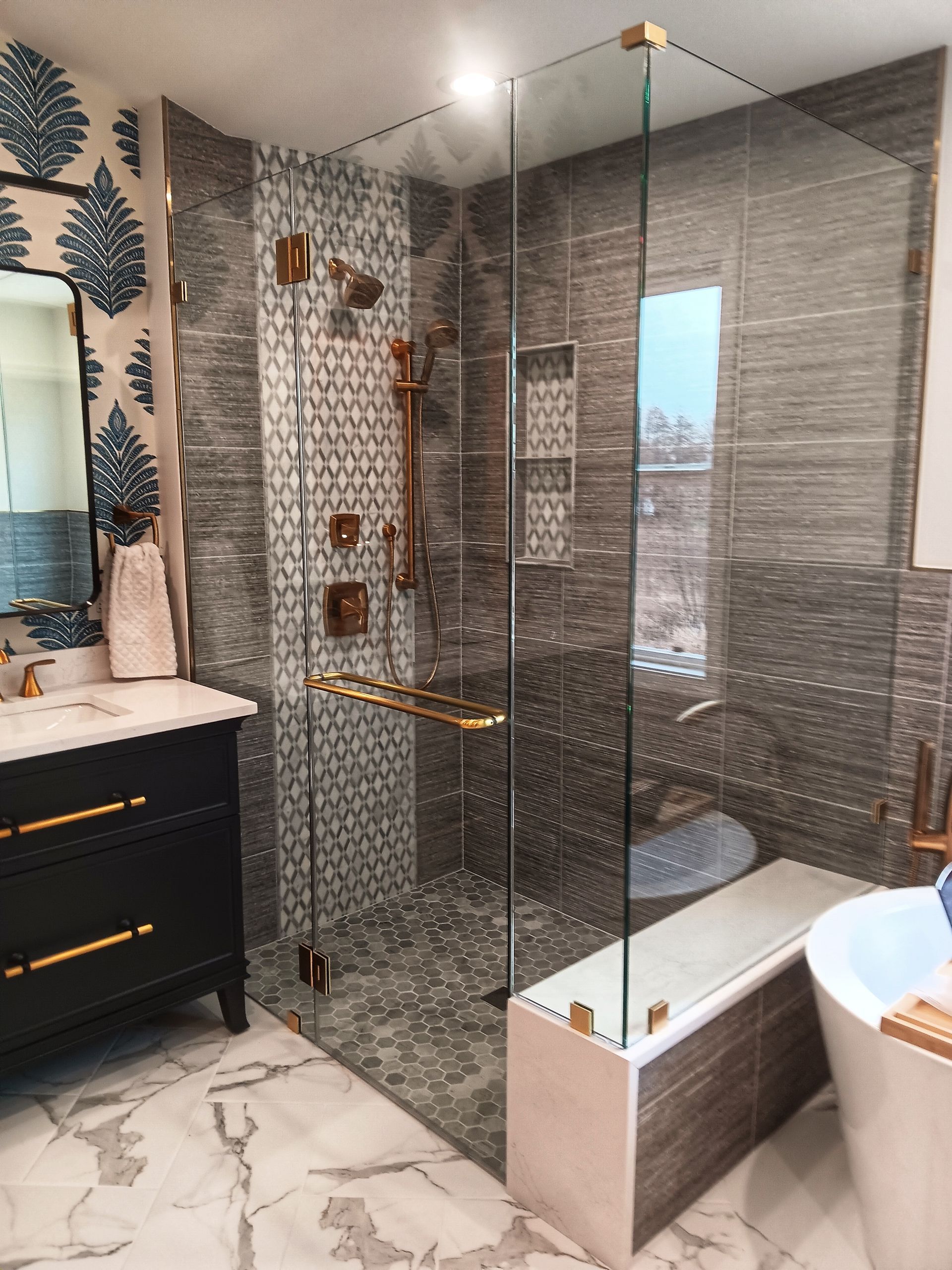 Luxurious modern bathroom with glass shower, gold fixtures, and patterned tiles.