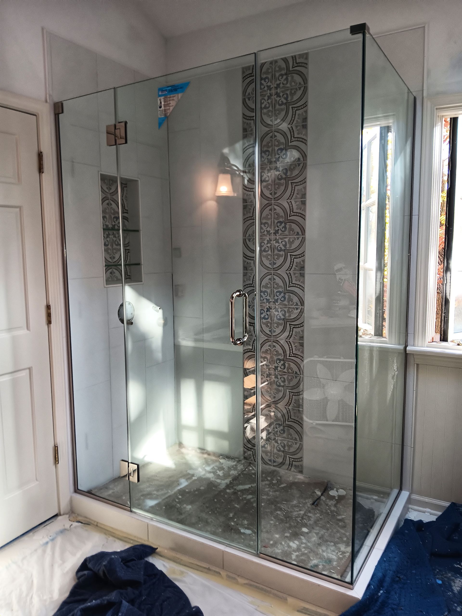 Frameless glass shower enclosure with decorative tile strip in a bathroom setting.