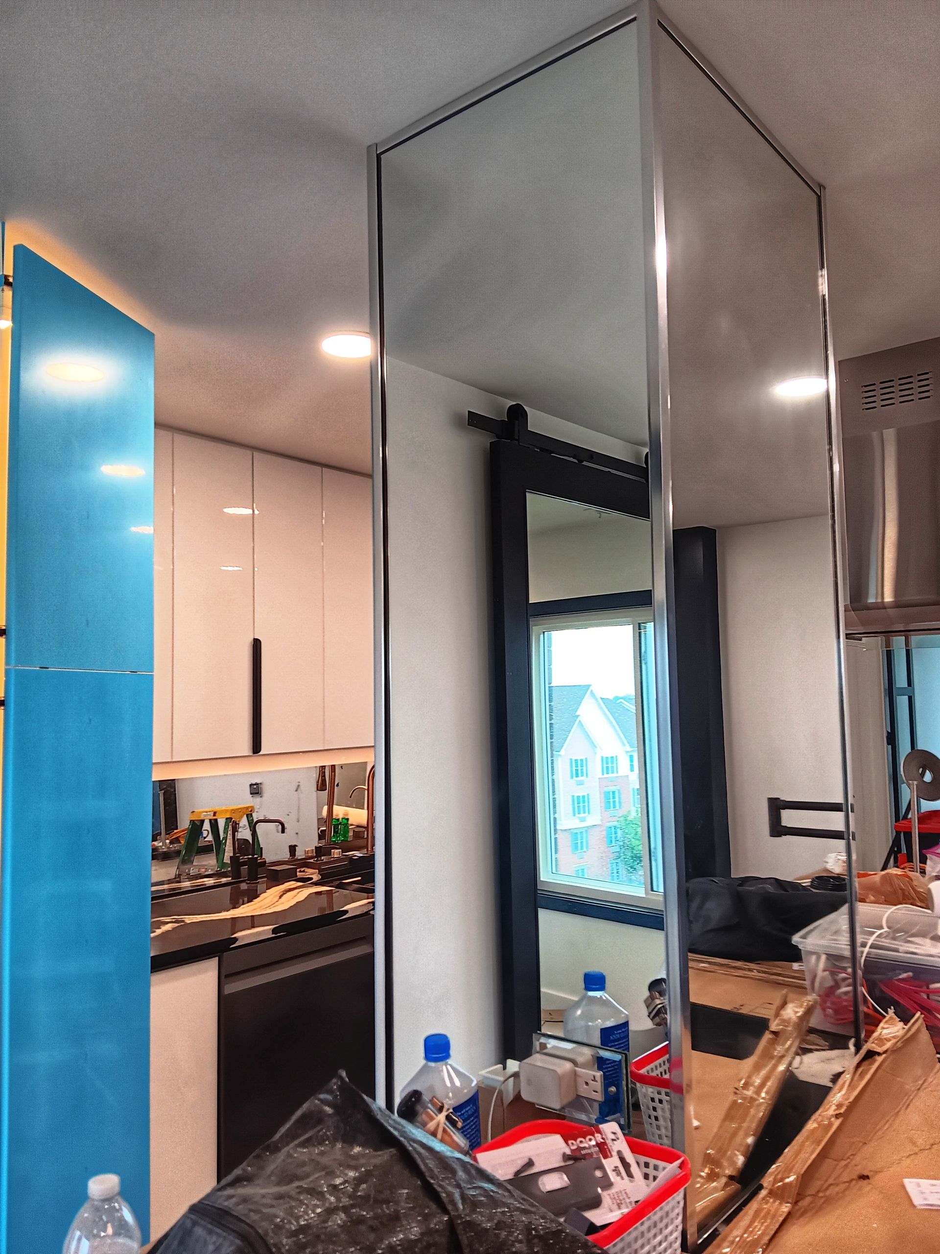 Tall mirrored pillar in a kitchen, reflecting the space. Blue cabinet on the left.