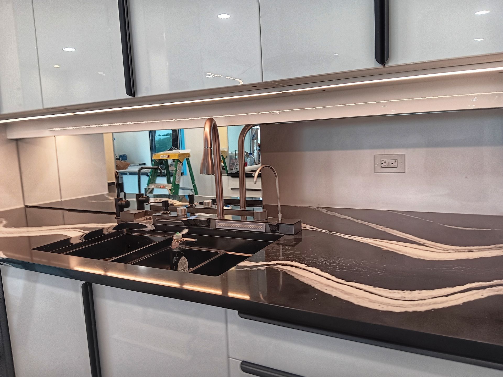 Modern kitchen counter with black and white patterned countertop, double sink, and chrome faucet.