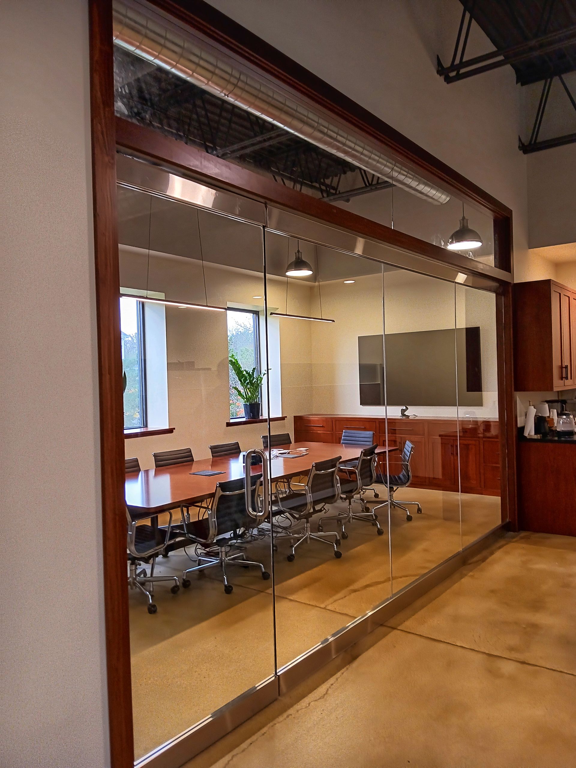 A conference room with a glass wall and a long table with chairs.