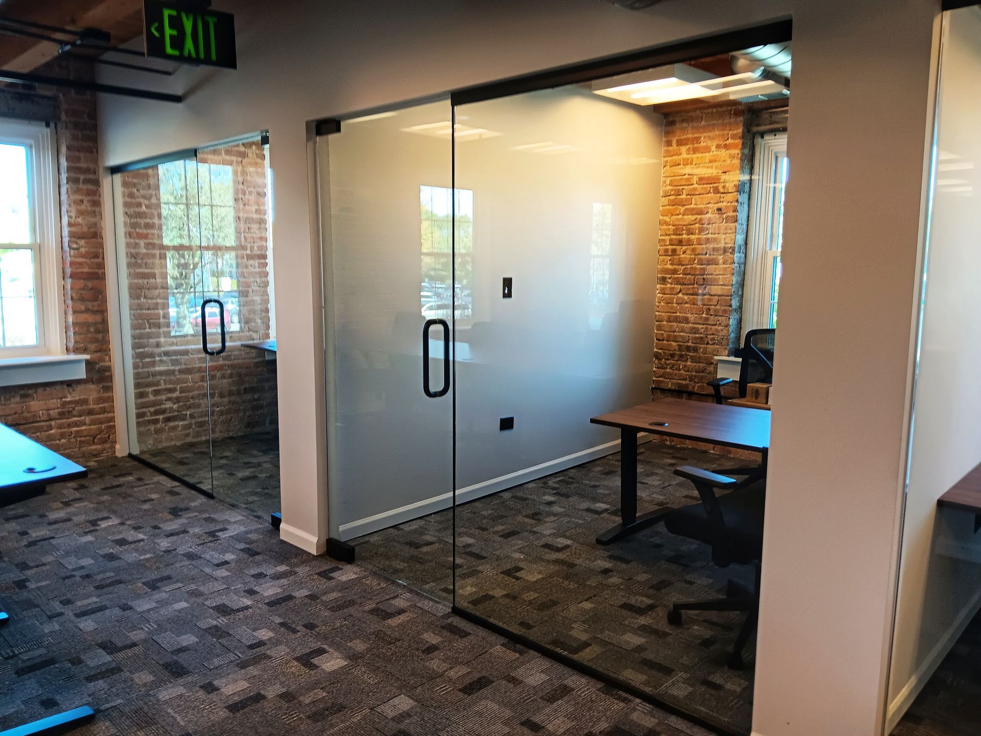 Offices with glass walls, brick accents, and carpet.