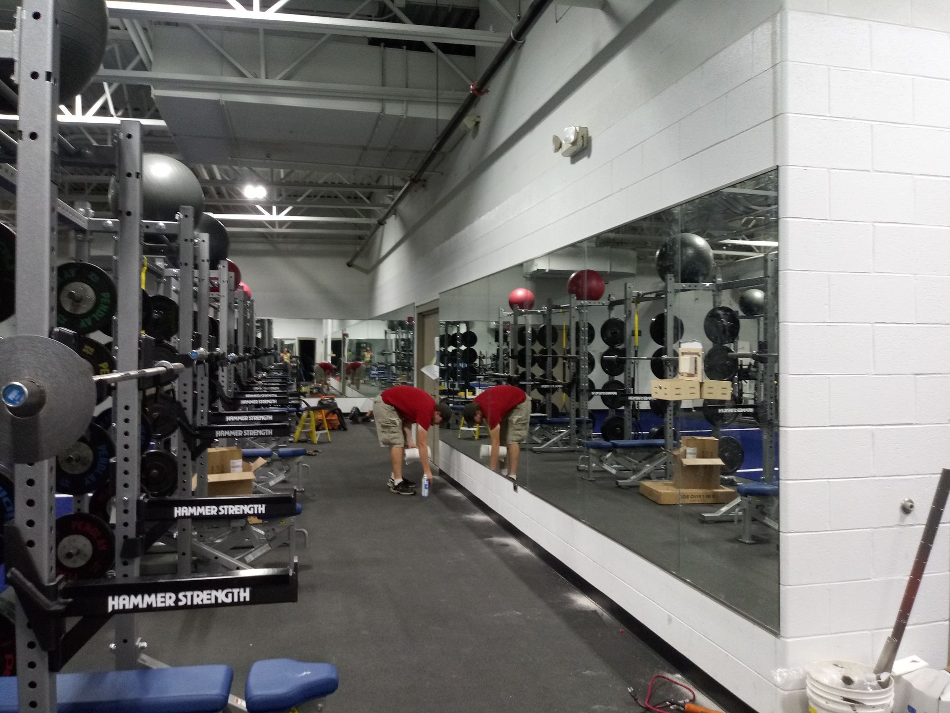 Weightlifting gym with mirrors, weights, and people.