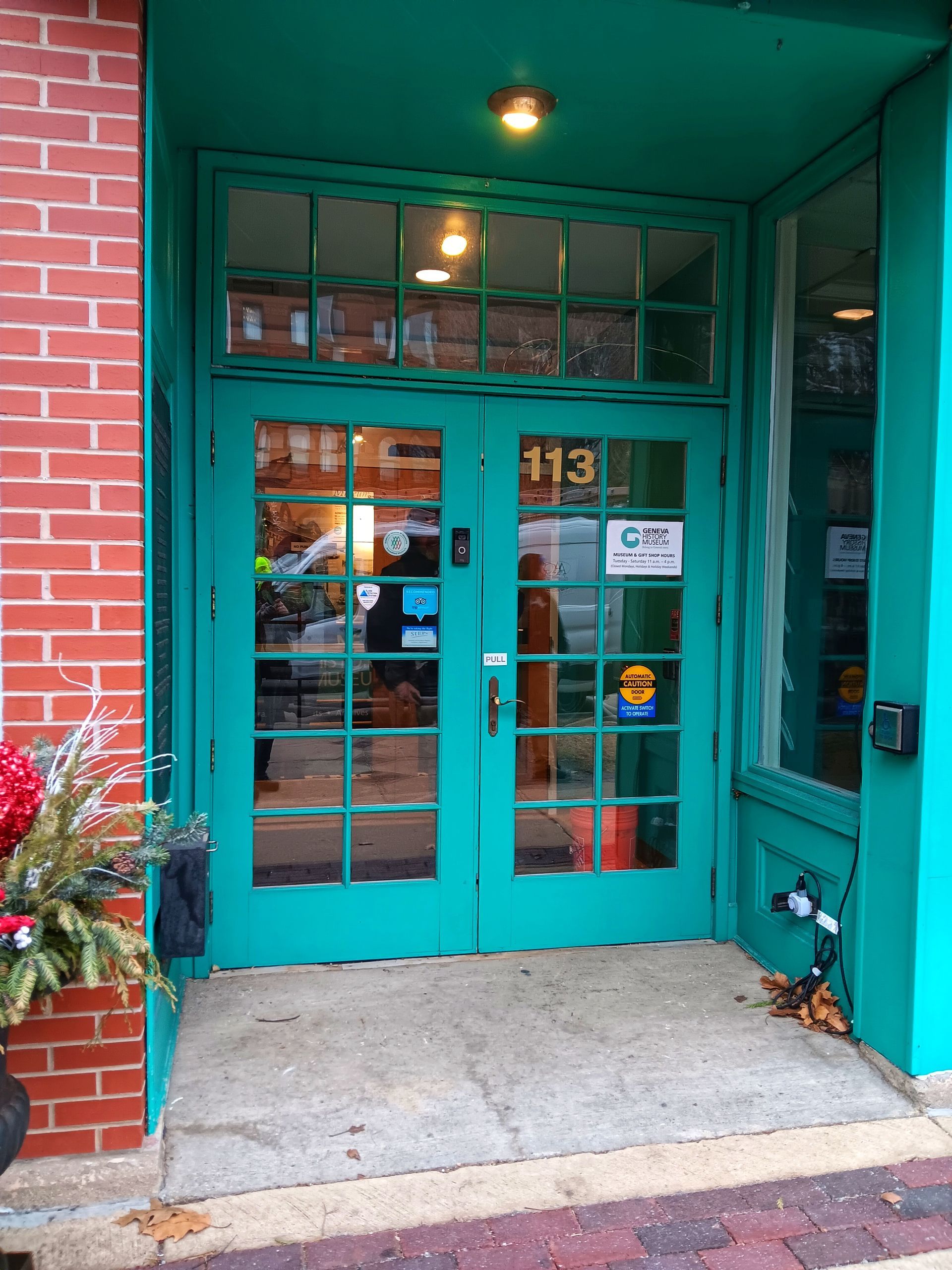 Teal double doors with glass panels at building entrance, brick and teal walls, number 