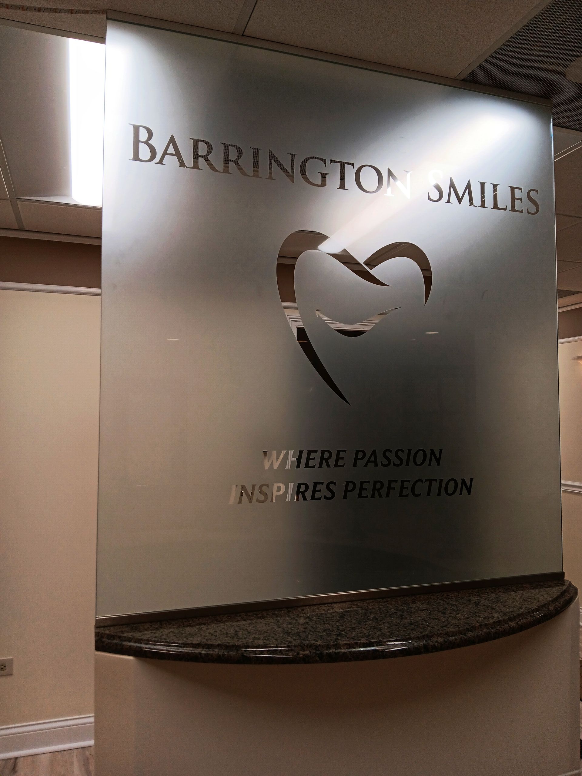 Sign for Barrington Smiles, frosted with a heart-shaped design, text: 