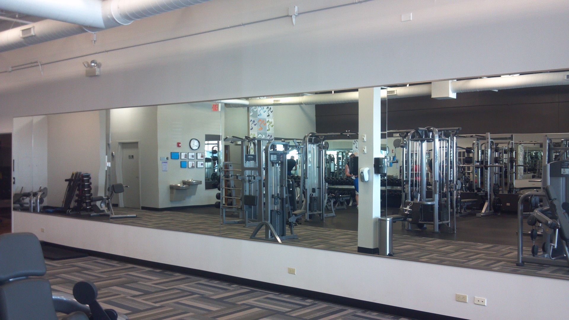 Gym interior with workout equipment and a large wall mirror.