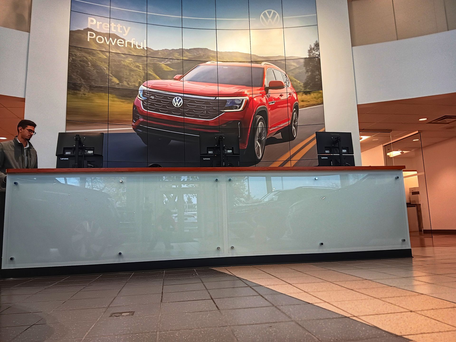 A red Volkswagen SUV in front of a reception desk at a dealership.