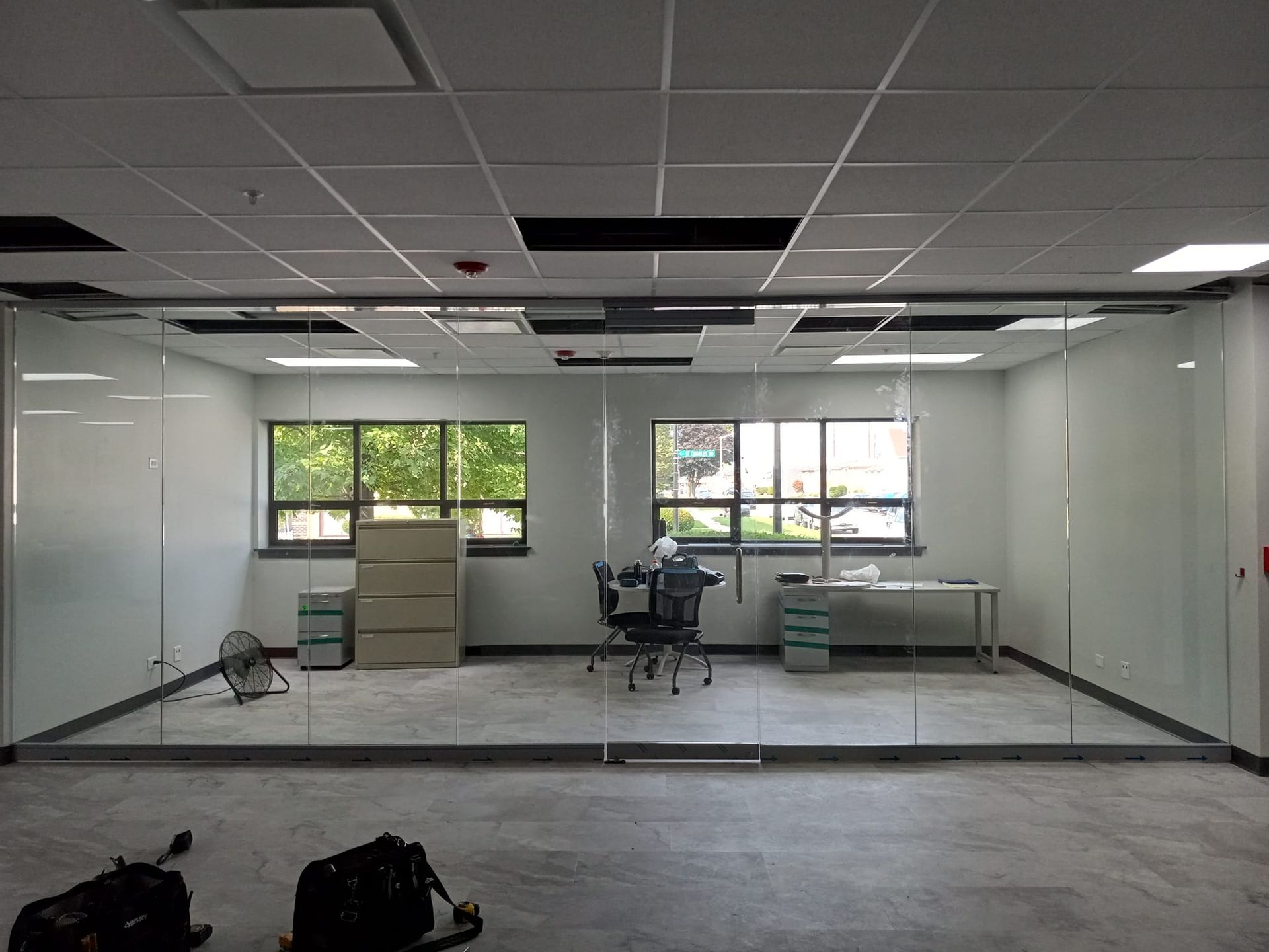 Office space with glass walls, windows, and office furniture.