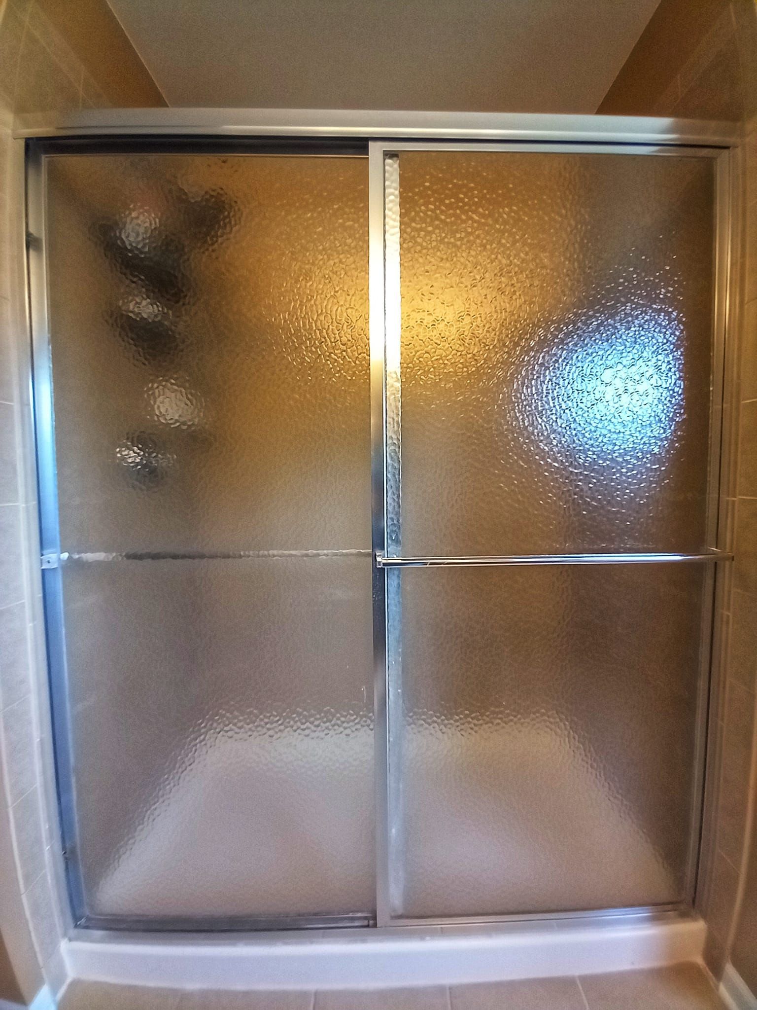 Shower with textured glass sliding doors and silver frame.