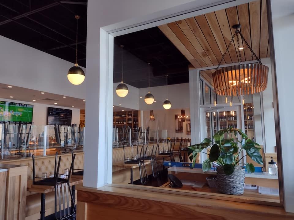 Restaurant interior with open pass-through. Bar area with upturned chairs, globe pendant lights, and decorative wooden chandelier.