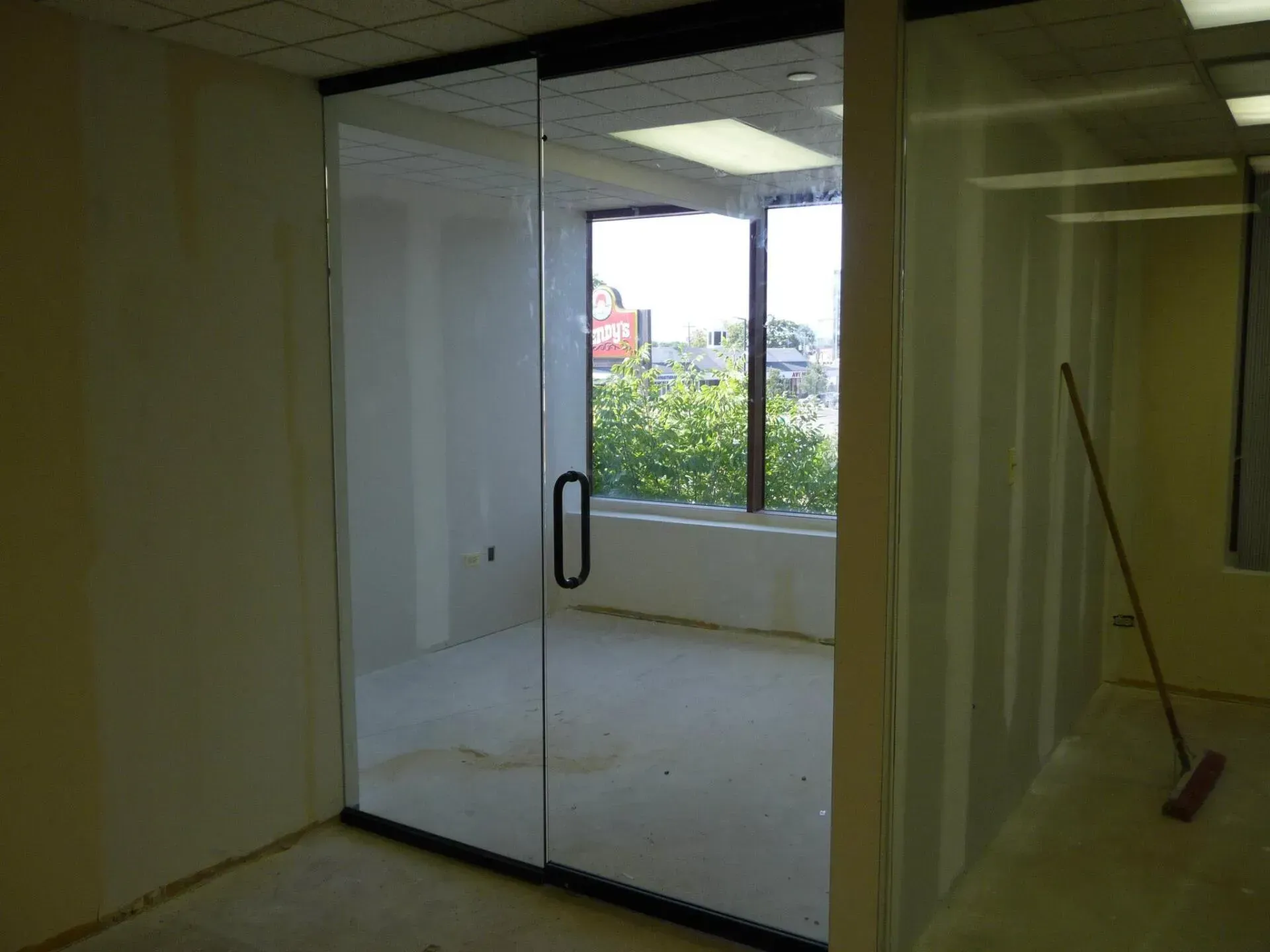 Glass sliding door to an office space. Daylight visible through windows.