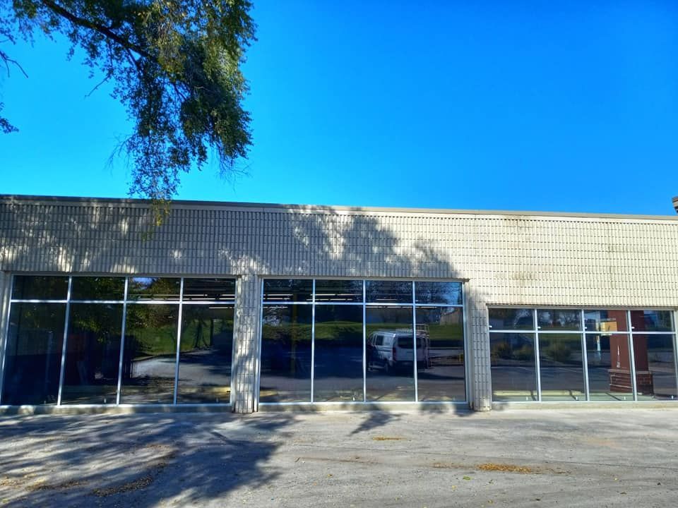 Building with large windows, reflecting a van and trees, under a clear blue sky.