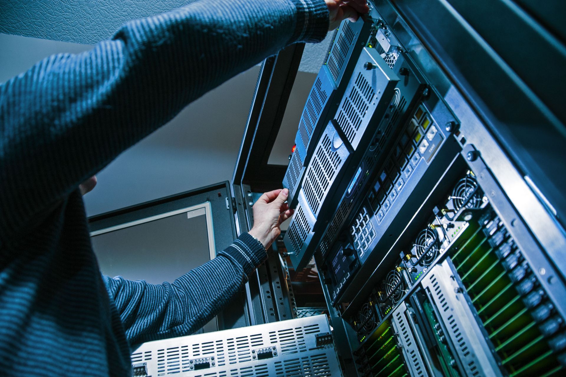 Person working on server equipment in a data center; pulling out a server component.