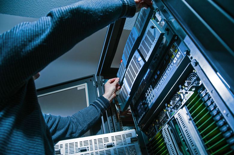Person working on server equipment in a data center; pulling out a server component.