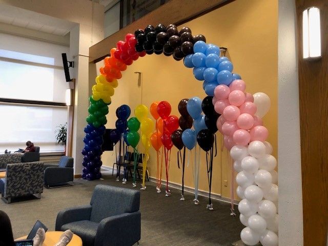 a rainbow colored balloon arch in a living room