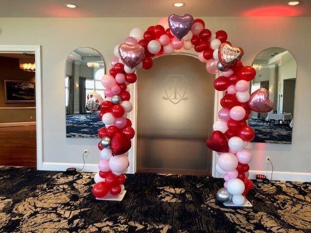 a room with a large arch made of red and pink balloons