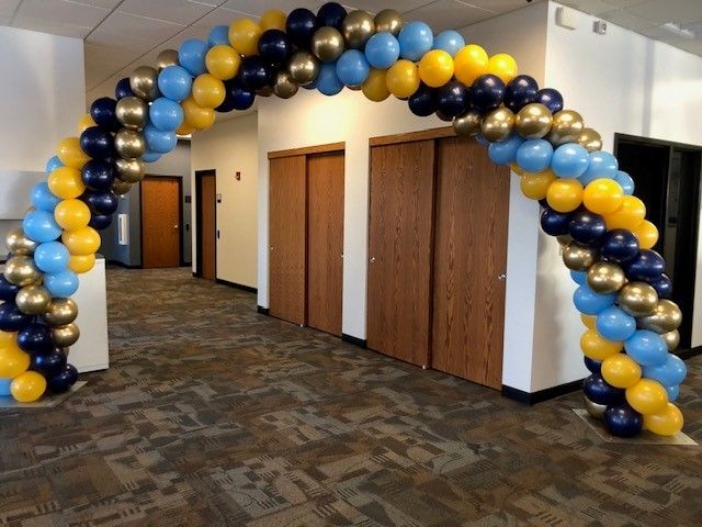a blue and yellow balloon arch in a hallway